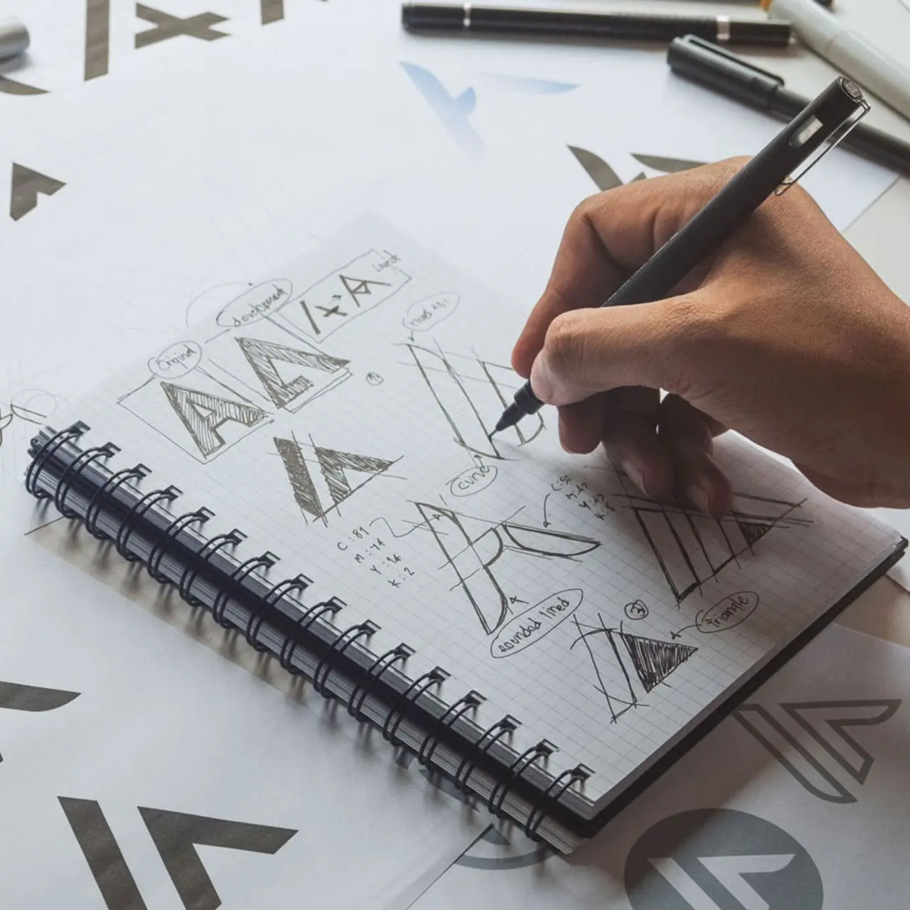 Imagen conceptual de un logotipo en proceso de diseño, con tipografía y elementos gráficos sobre una mesa, representando identidad visual profesional y estrategia de marca.